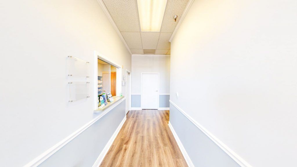 A long hallway with wooden floors and white walls in a building.