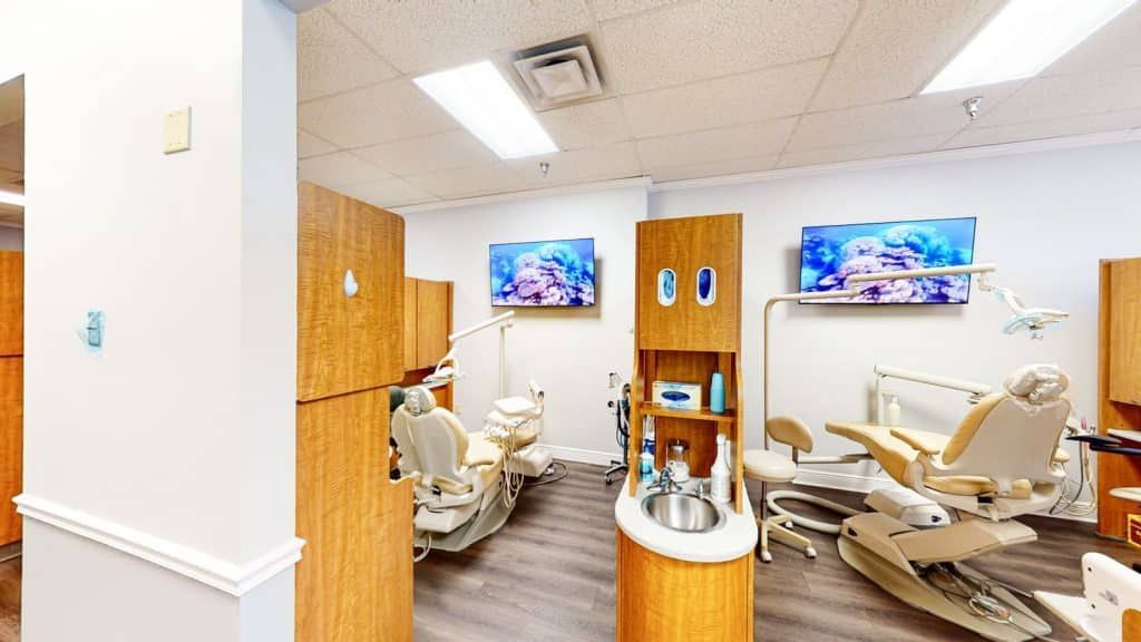A dental office with two dental chairs and a sink.