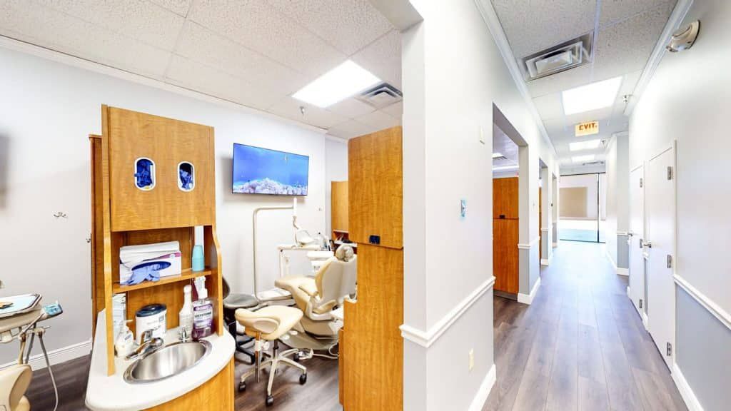 A dental office with a dental chair and a sink in a hallway.