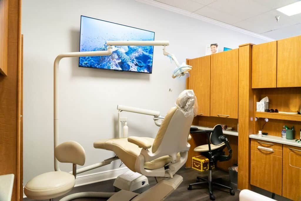 A dental office with a dental chair and a television on the wall.