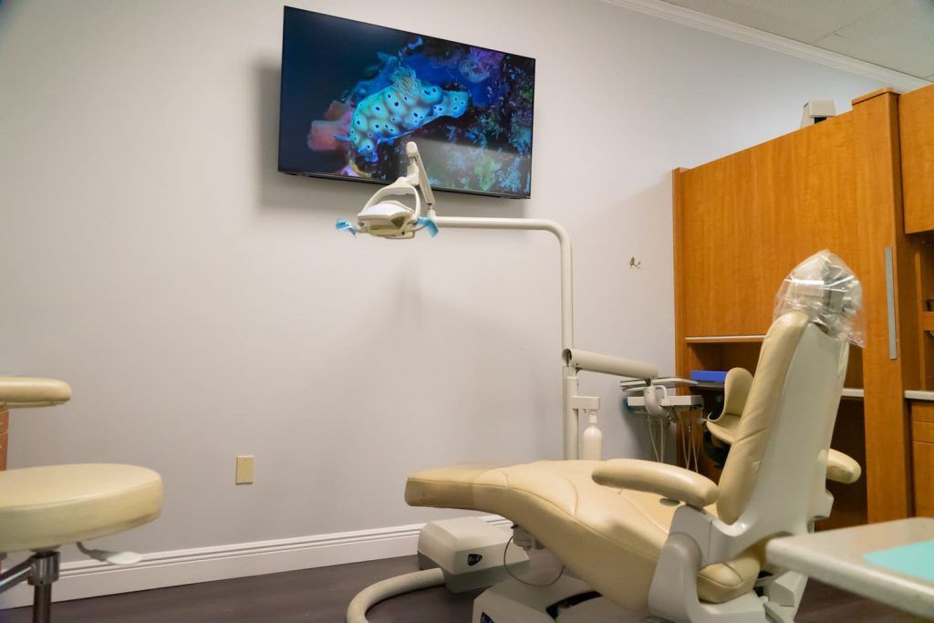 A dental office with a dental chair and a television on the wall.