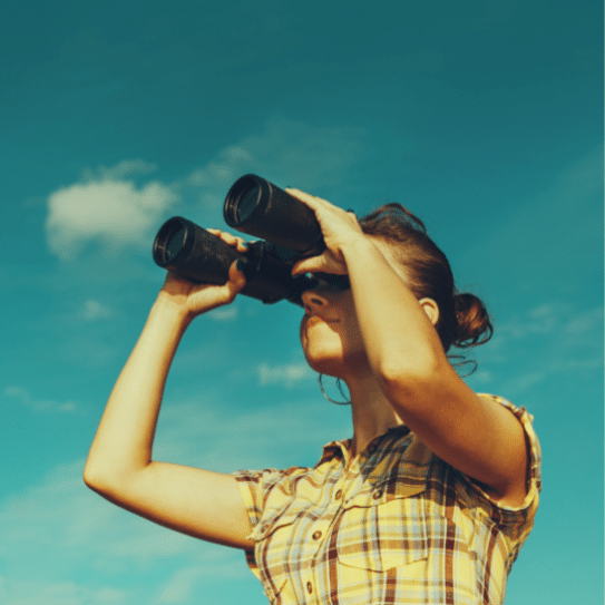 A woman in a plaid shirt is looking through binoculars