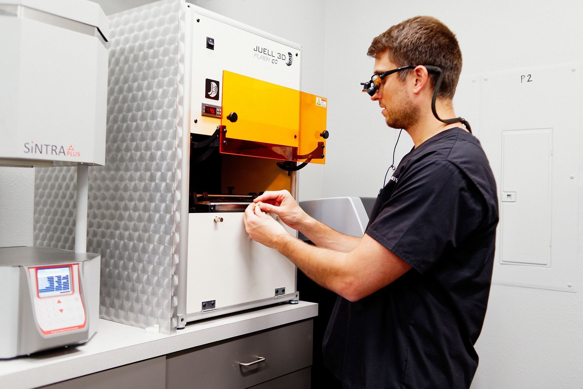 A man wearing glasses is working on a machine in a lab.