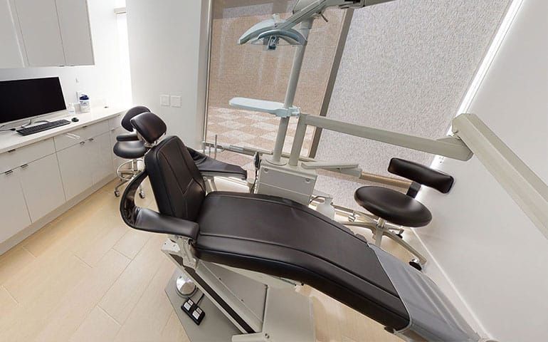 A dental office with a dental chair and a computer
