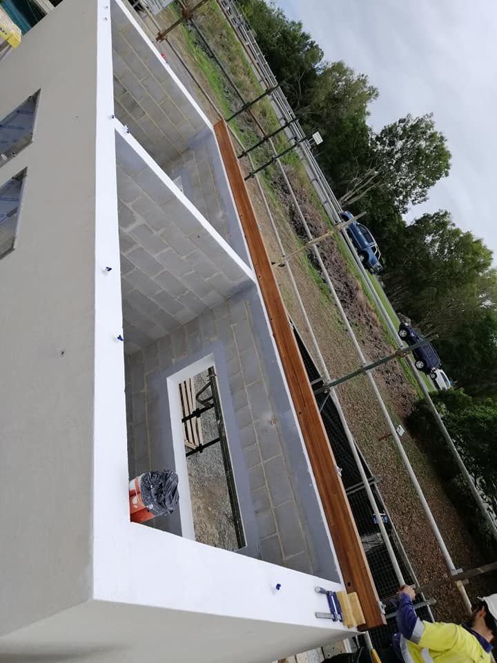 A Man in A Yellow Hard Hat Is Working on A Building — Semrau Constructions In Bentley Park, QLD