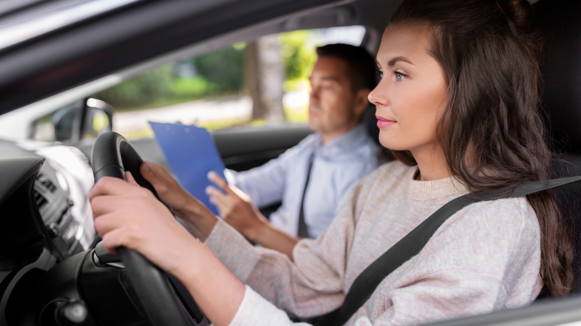 A man is teaching a woman how to drive a car.