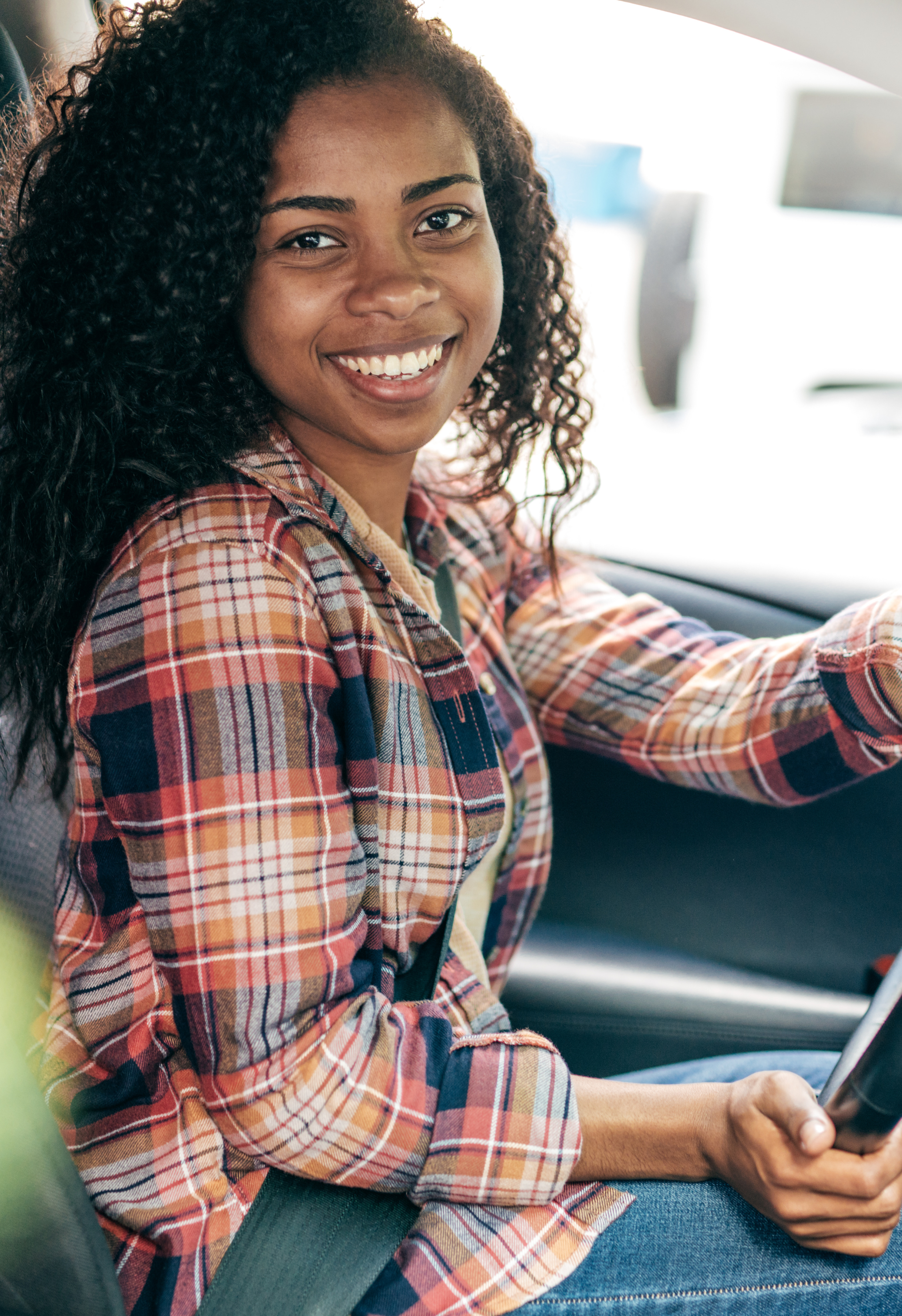 A woman is sitting in the back seat of a car looking at her phone.