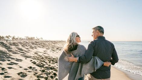 A man and a woman are walking on the beach.