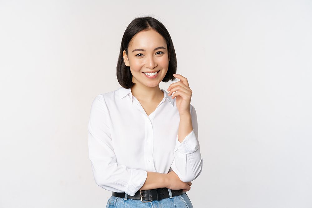 A woman in a white shirt is smiling and holding a credit card.