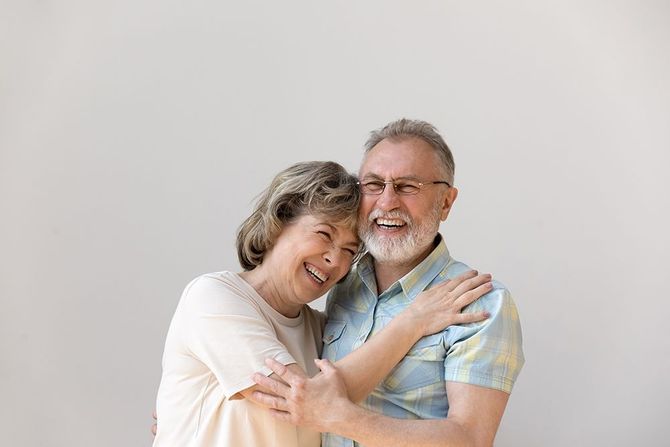 A man and a woman are hugging each other and smiling.