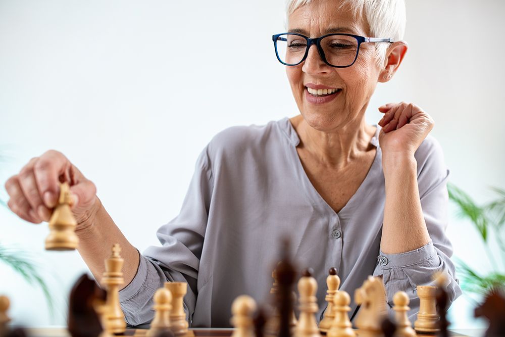 An elderly woman is playing a game of chess.
