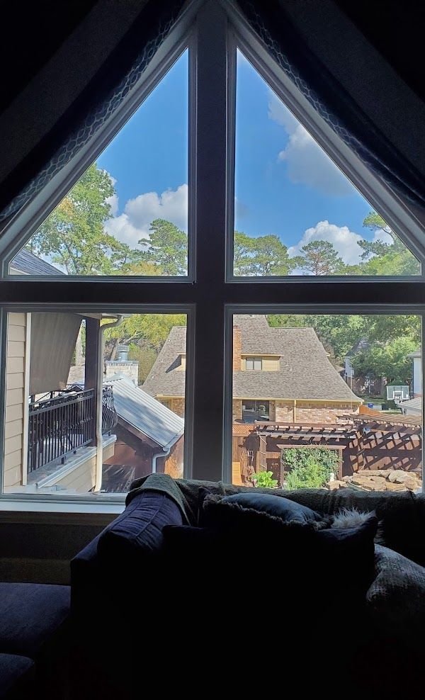 A living room with a couch and a large window with a view of a house.