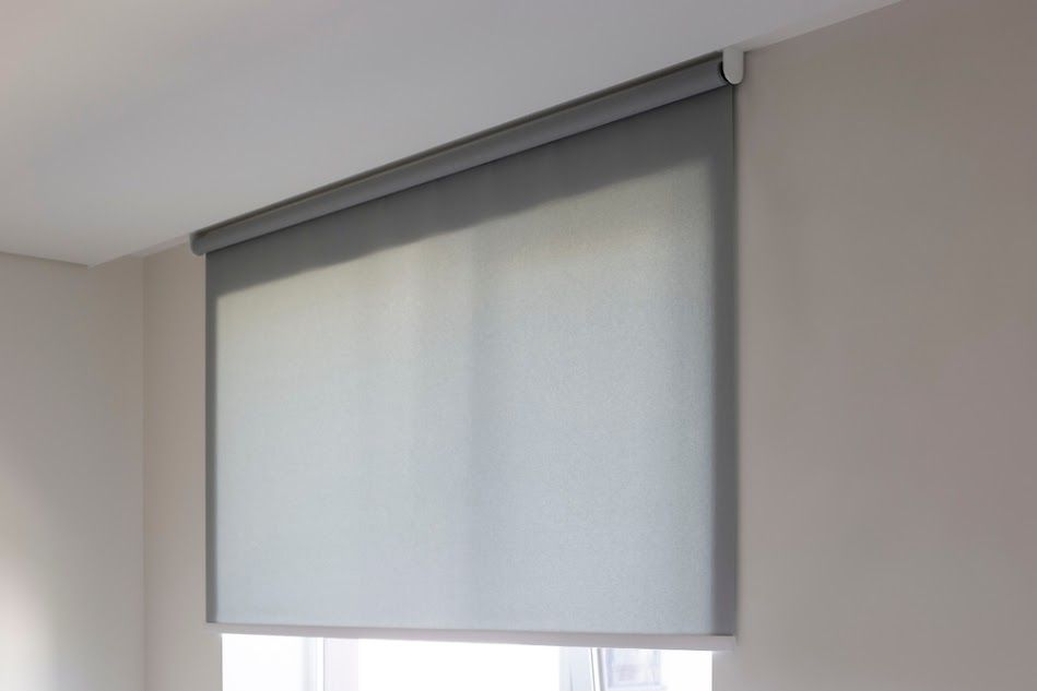 A roller blind is hanging on a window in a room.
