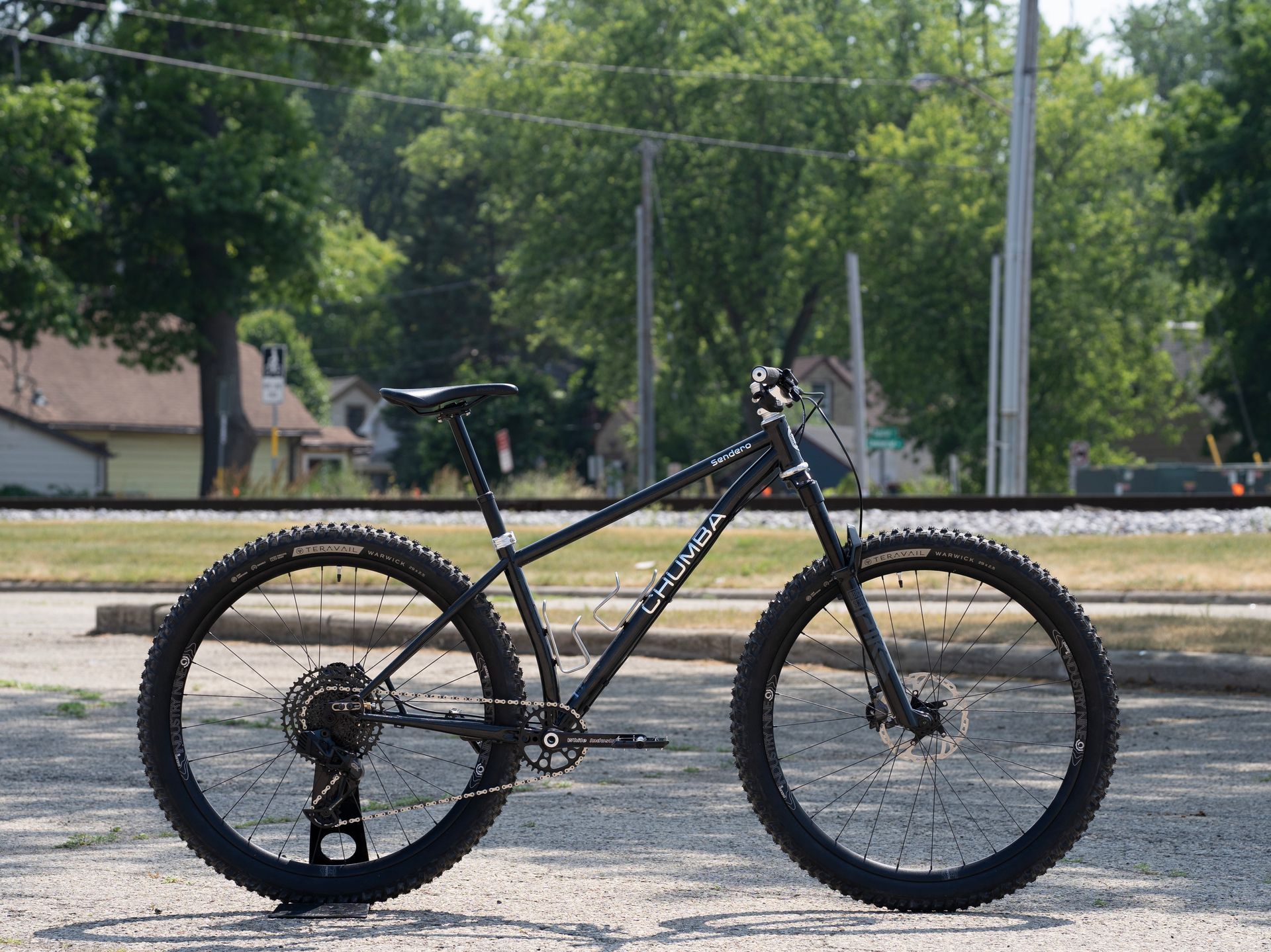 A black mountain bike is parked on the side of the road.