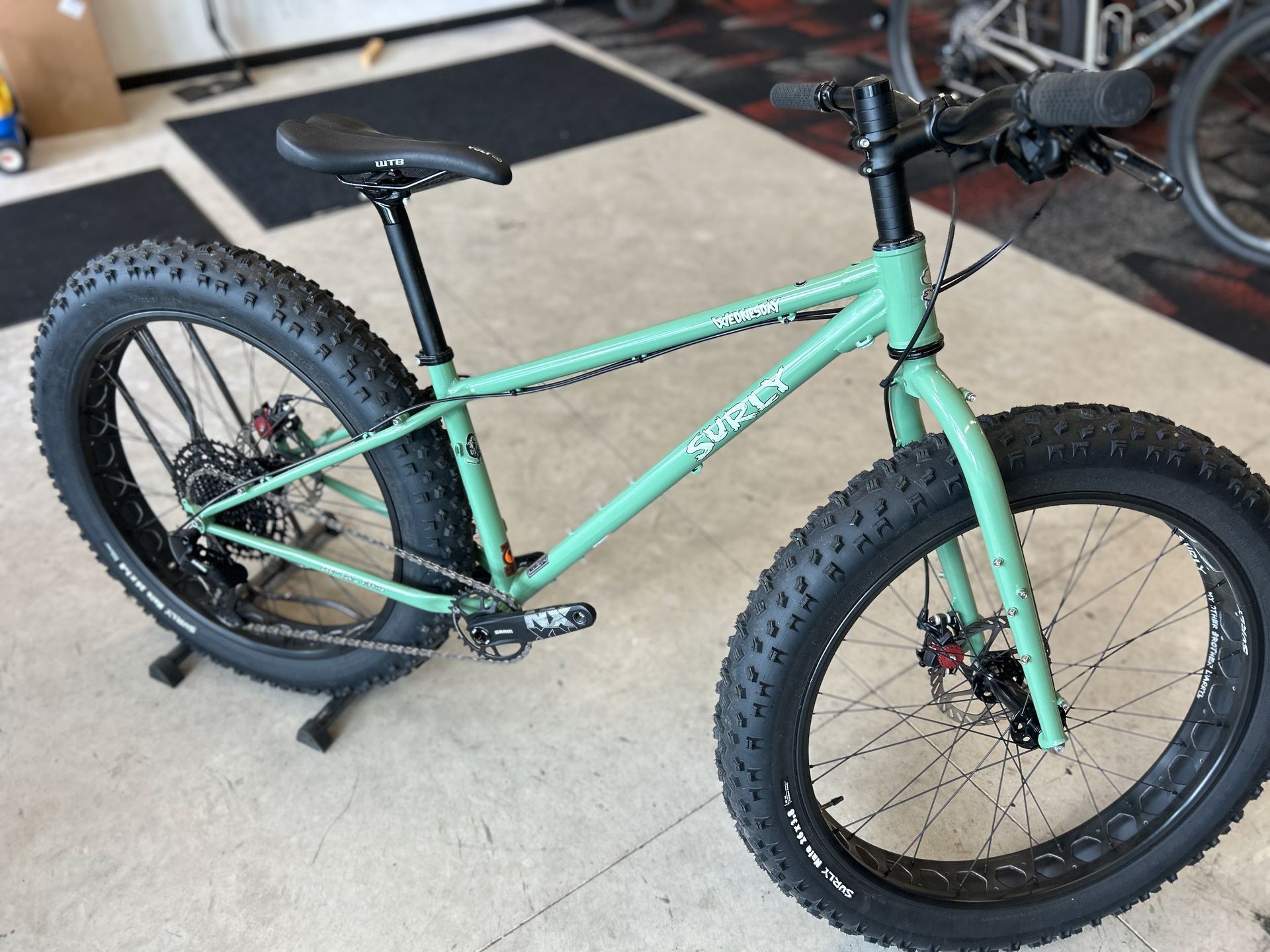 A green bicycle with big tires is sitting on a stand in a garage.