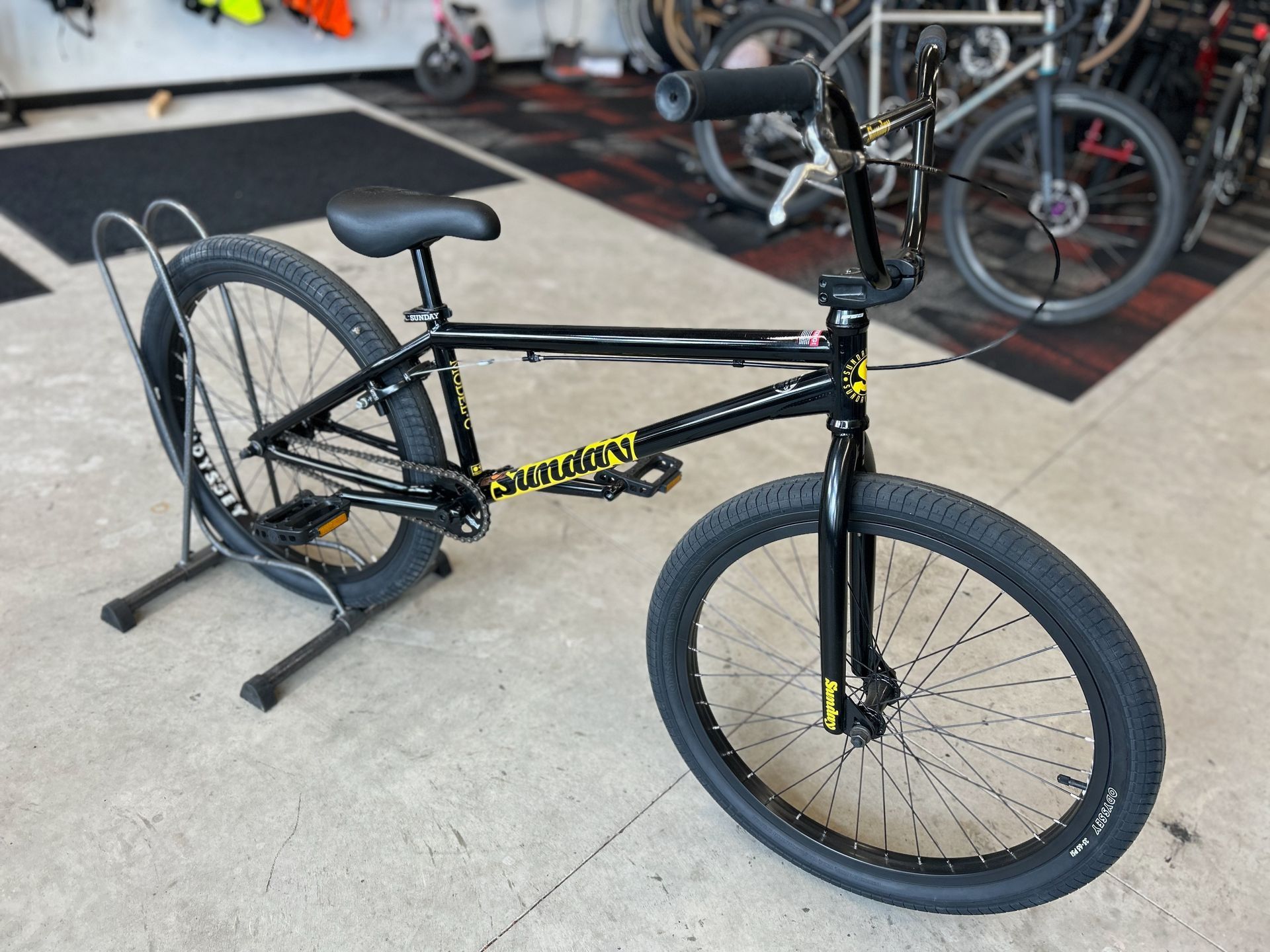A black bmx bike is sitting on a stand in a garage.