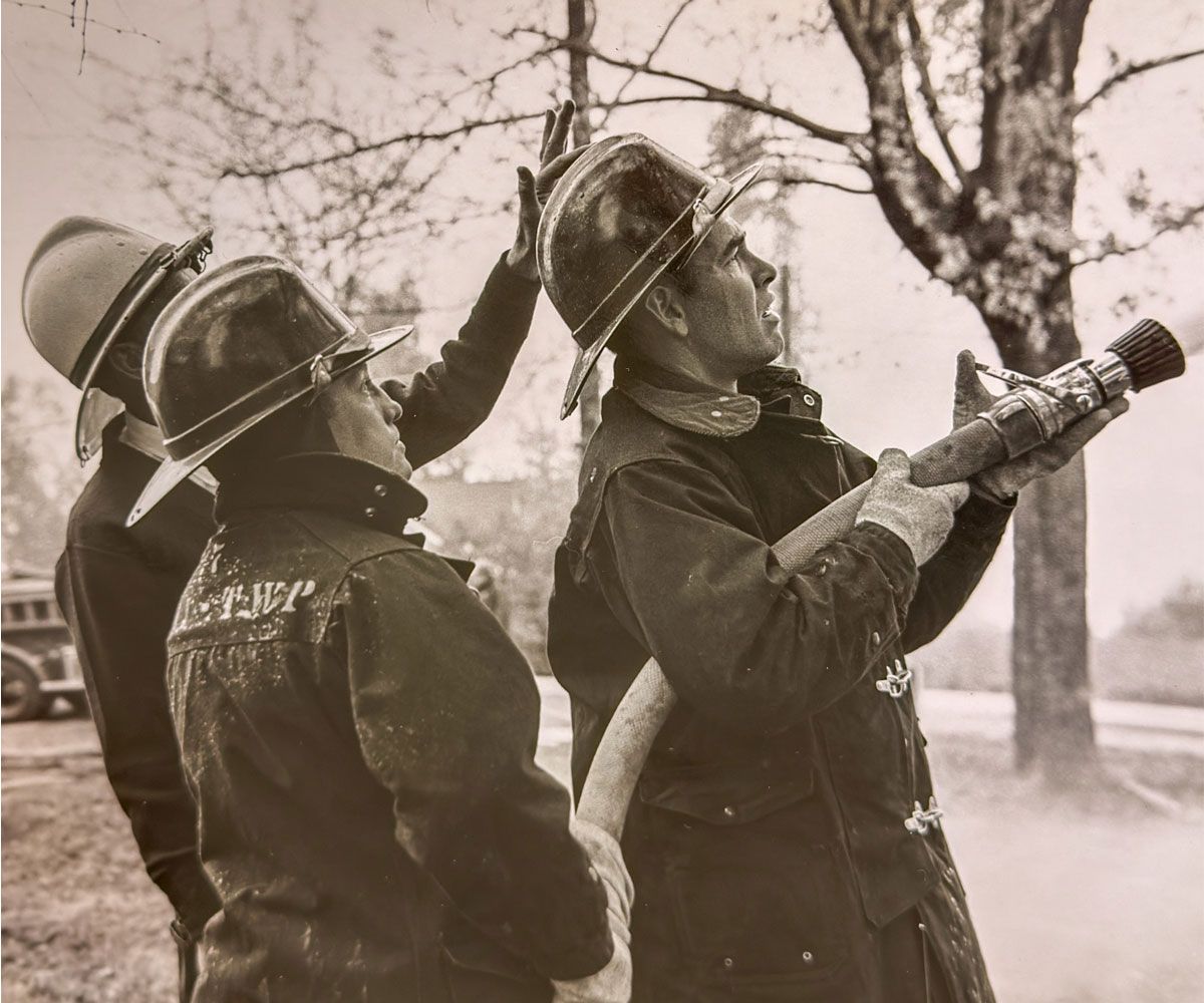 Tri Township black and white historical photo of 3 firemen holding a hose circa 1950s