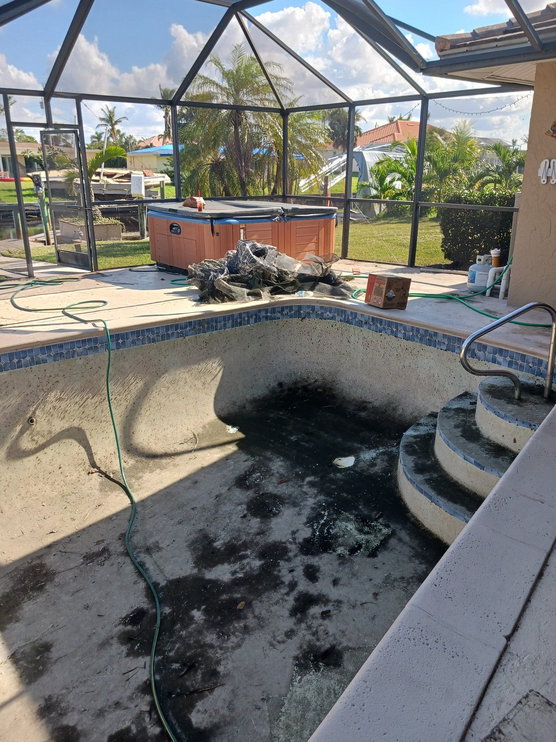 A dirty swimming pool with a hot tub in the background.