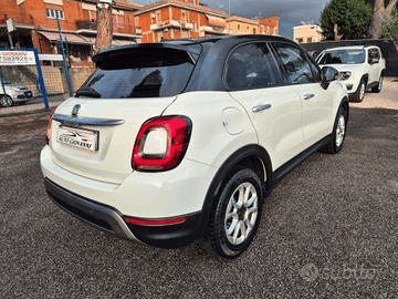 Hyundai i10 berlina color argento parcheggiata sulla ghiaia. Scatto diurno con altre auto ed edifici visibili sullo sfondo.