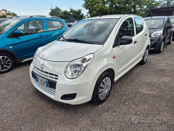 Una Suzuki Alto bianca parcheggiata in un parcheggio insieme ad altre auto.