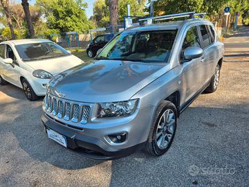 Una Jeep Compass argentata parcheggiata in strada accanto a una Fiat bianca. L'ambientazione è all'aperto, in una giornata di sole.