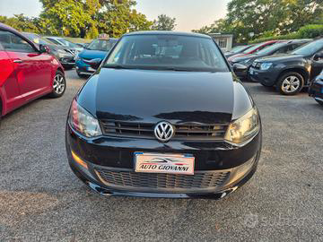 Un'auto Volkswagen nera parcheggiata presso una concessionaria, con vista frontale che mostra la griglia, l'emblema e i fari.