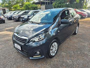 Un'autovettura Peugeot 108 hatchback grigio scuro parcheggiata in un parcheggio insieme ad altre auto in una giornata di sole.