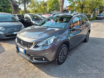 Un SUV Peugeot 2008 grigio parcheggiato su un piazzale asfaltato. Sullo sfondo si vedono diverse altre auto.