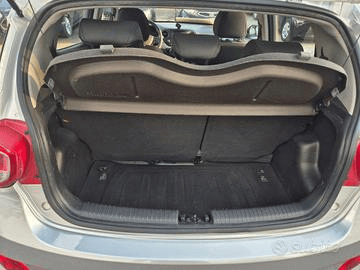 Apertura del bagagliaio di un'auto argentata, che rivela l'area di carico con rivestimento nero.