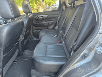 Sedili posteriori dei passeggeri di un SUV Nissan X-Trail grigio. I sedili in pelle nera sono puliti, con poggiatesta visibili.