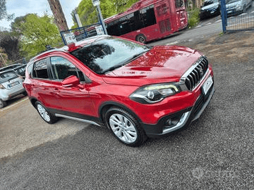 Un SUV Suzuki SX4 S-Cross rosso parcheggiato su una strada asfaltata con un autobus sullo sfondo.