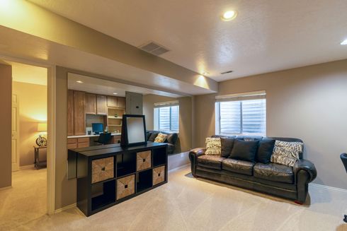 A living room in a basement with a couch and a television.