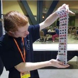 A man is holding a stack of playing cards in his hands.