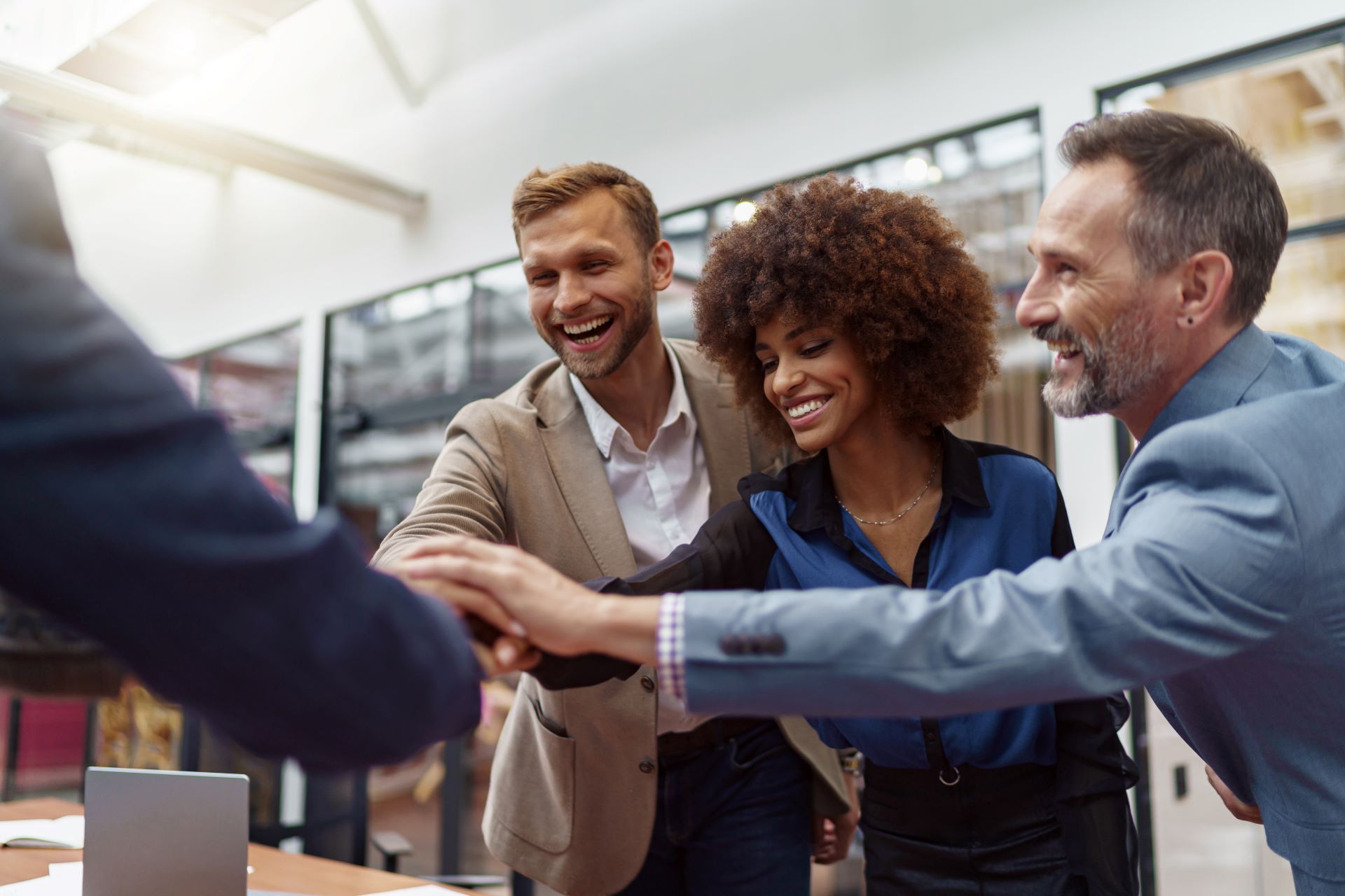 A group of business people are putting their hands together in an office.