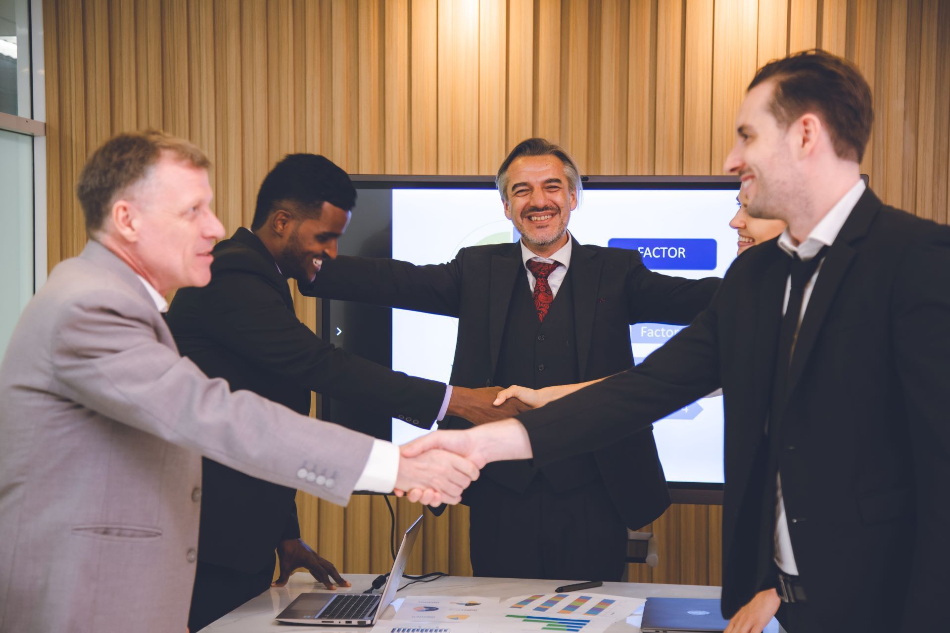A group of businessmen are shaking hands in a conference room.