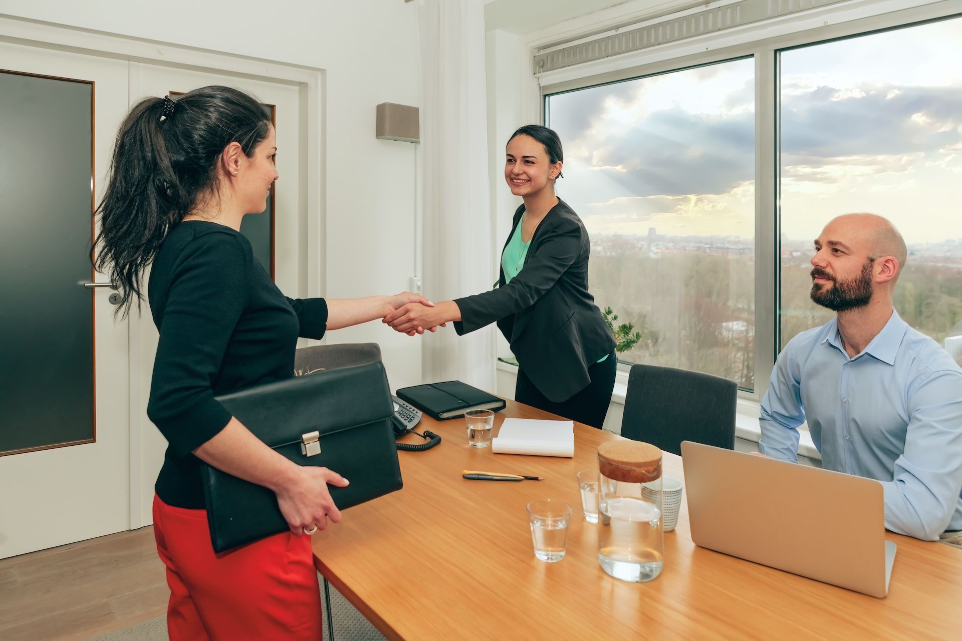 A woman is shaking hands with a man in a conference room.