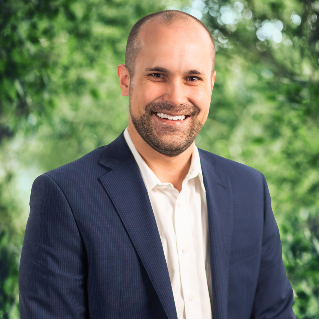 A man in a suit and white shirt is smiling for the camera.