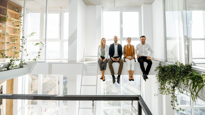 A group of people are sitting on a balcony in an office building.