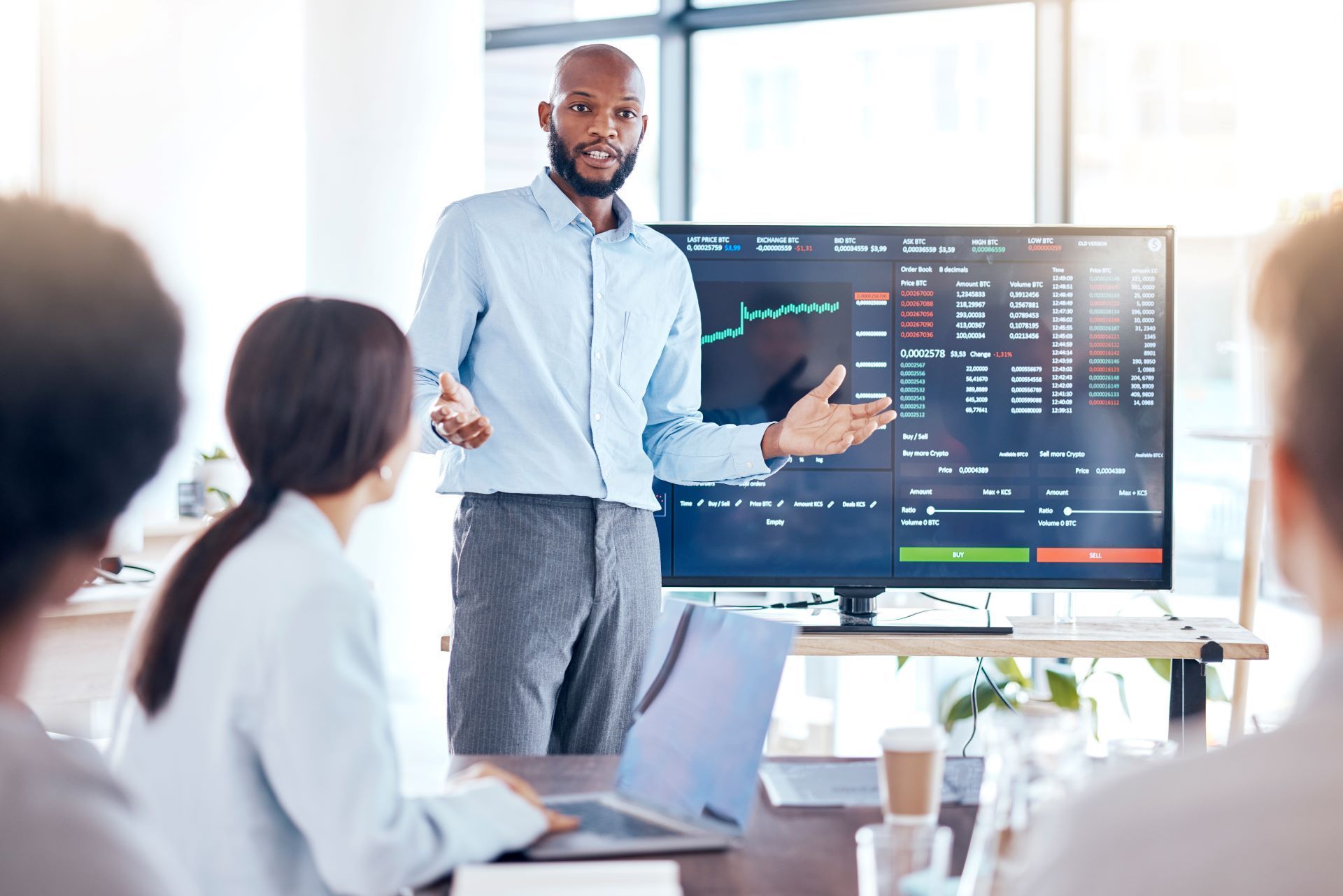 A man is giving a presentation to a group of people in front of a computer screen.