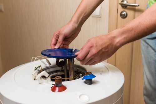 un homme répare un chauffe-eau dans une salle de bain.