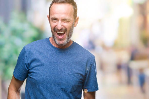 A man with a beard is wearing a blue t-shirt and smiling.