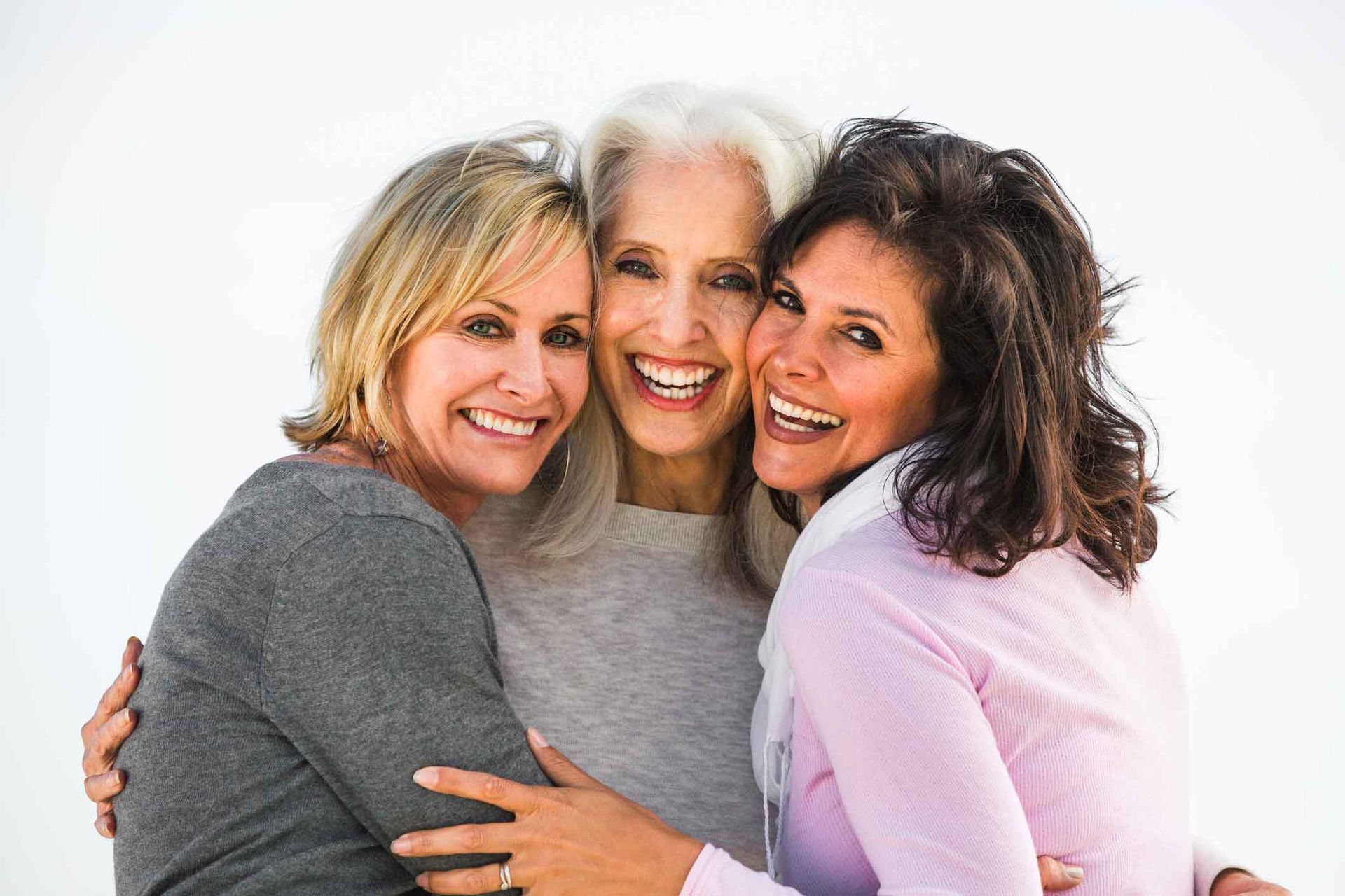 Three women are hugging each other and smiling for the camera.