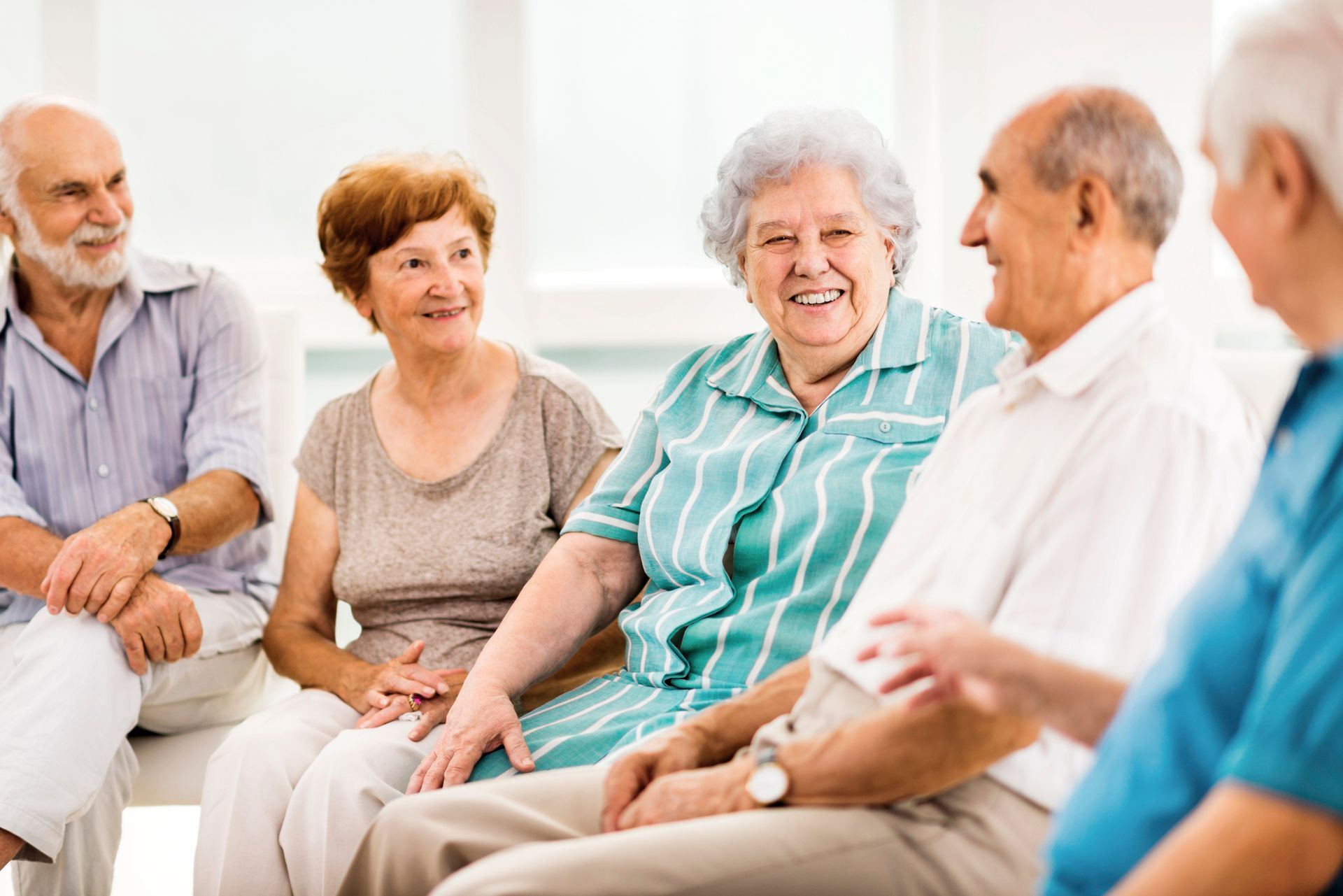A group of elderly people are sitting in a circle talking to each other.