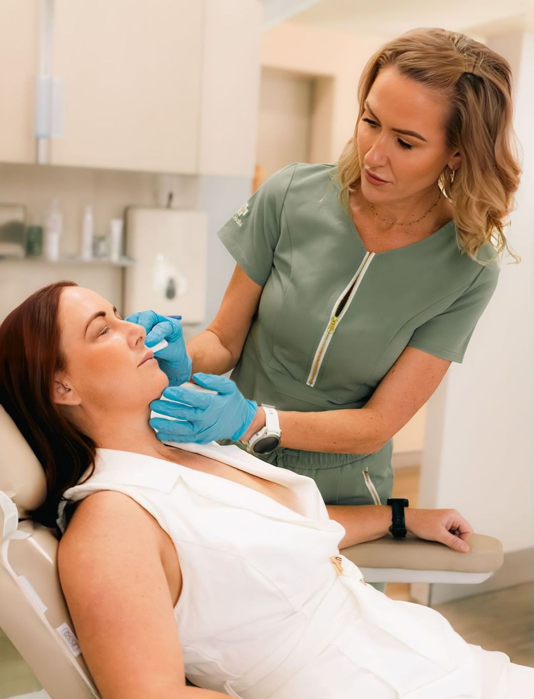 Woman receiving facial injections from a medical professional wearing gloves, in a clinic.