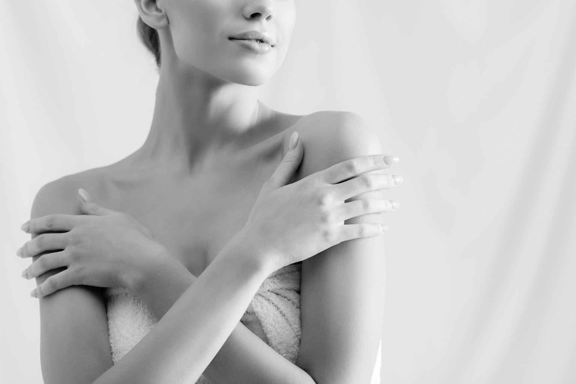 Woman with arms crossed over chest, wrapped in a towel, in grayscale.