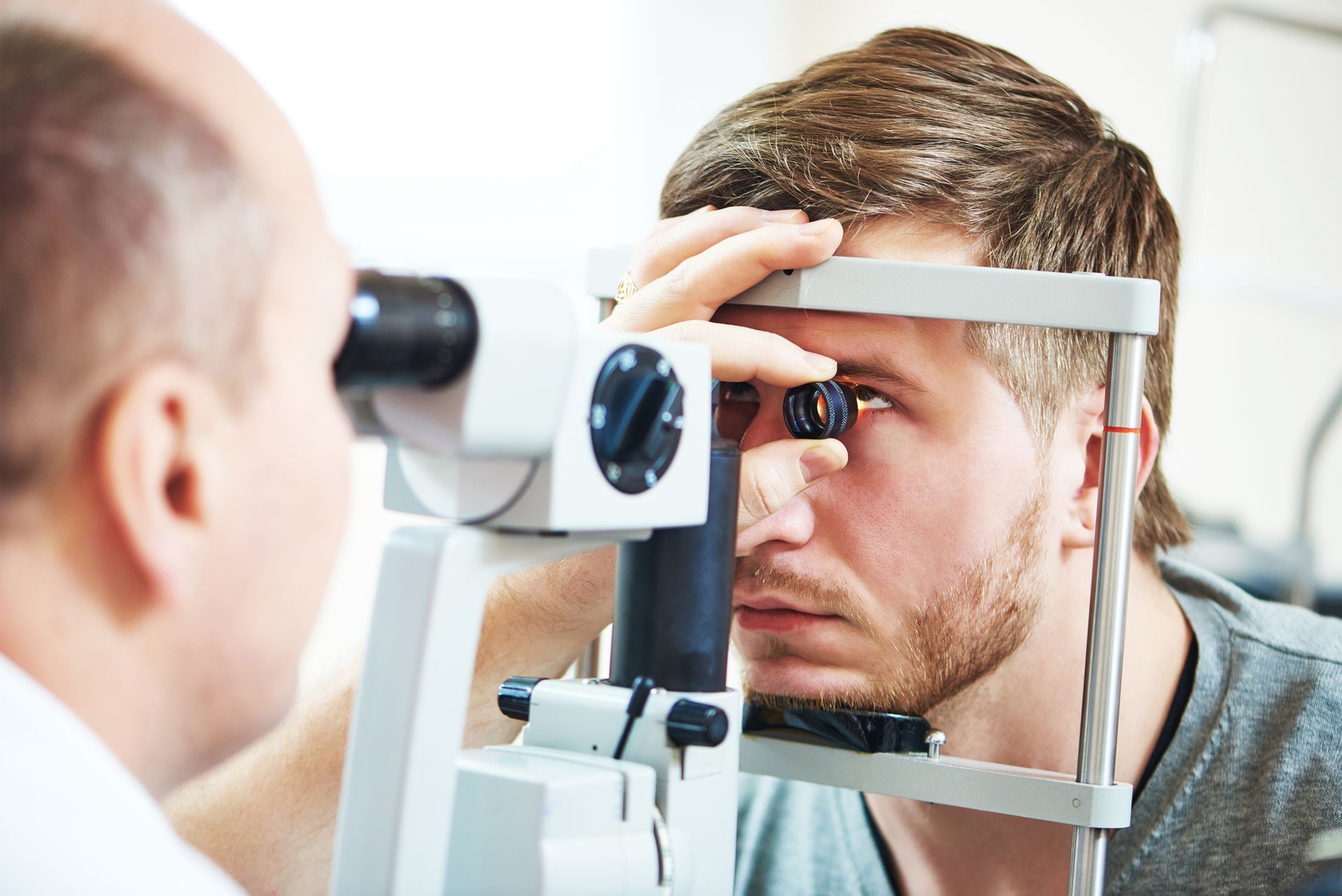 Man getting an eye exam using a slit lamp by an optometrist.