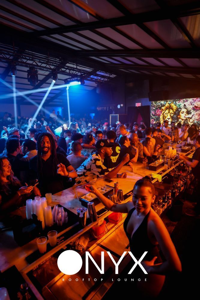 Inside a nightclub, people gather near a lit-up bar. The Onyx logo is visible.