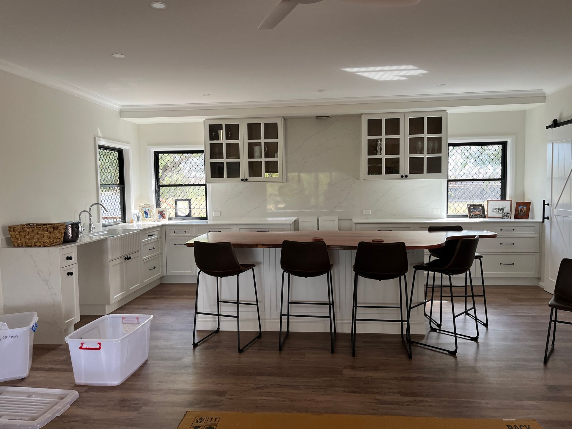 A White Kitchen Featuring a Wooden Island With Four Dark Chairs — Priority Painters in Gladstone Central, QLD