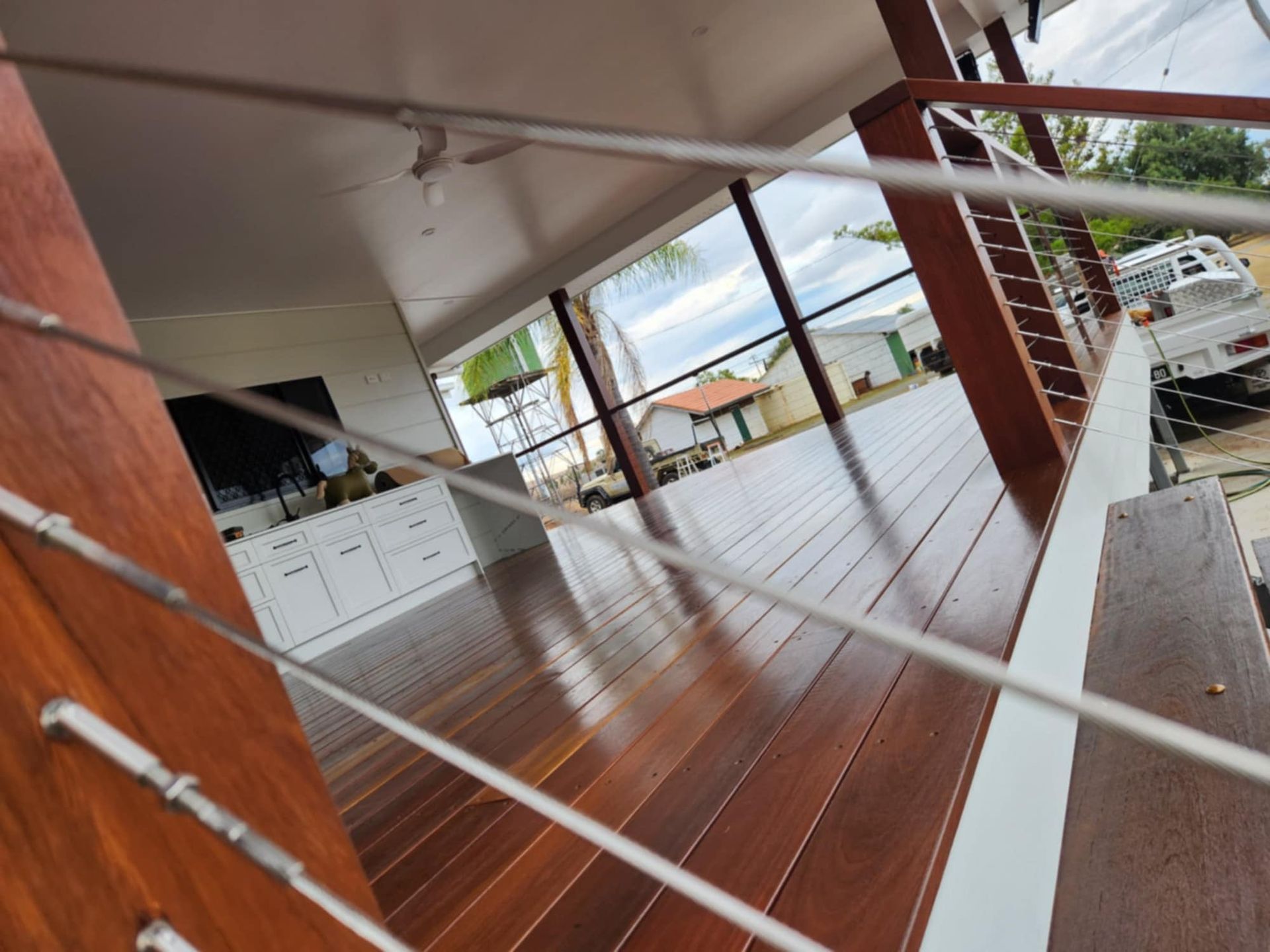 A Wooden Deck With a Cable Railing Overlooking a House — Priority Painters in Gladstone Central, QLD