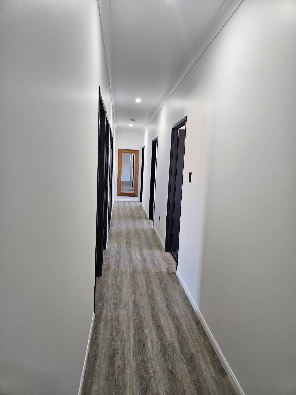 A Straight Indoor Hallway With Light Gray Walls — Priority Painters in Gladstone Central, QLD